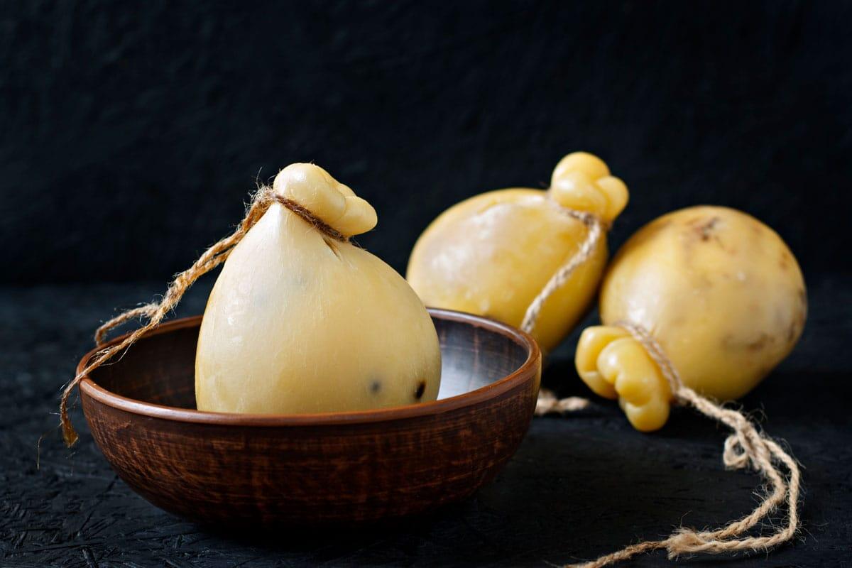 Il Caciocavallo silano DOP è tra i formaggi più apprezzati al mondo - Cheese Caciocavallo in a plate on a black background. Cheese pear.