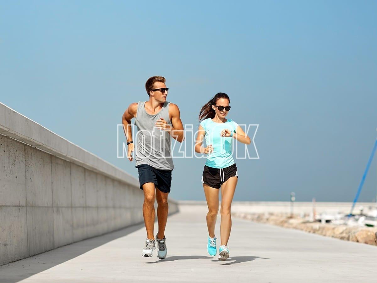 Lifestyle / L'attività fisica è un potente antistress, parola di esperti - sport, technology and lifestyle concept - happy couple with fitness tracker running along pier in summer