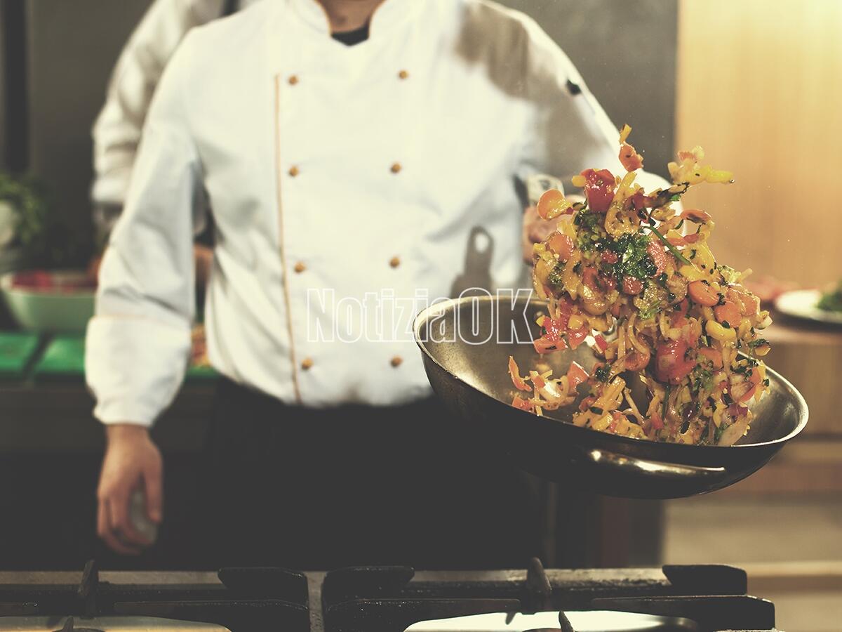 Le grandi firme Michelin in cucina per la Caretta Calabria Conservation Onlus - Young male chef flipping vegetables in wok at commercial kitchen