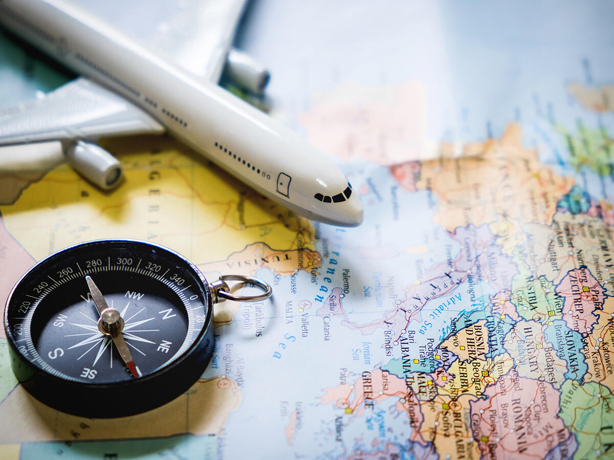 Sciopero aerei 20 giugno, cosa fare per salvare il viaggio - selective focus of miniature tourist on compass over map with plastic toy airplane,abstract background to travel concept.