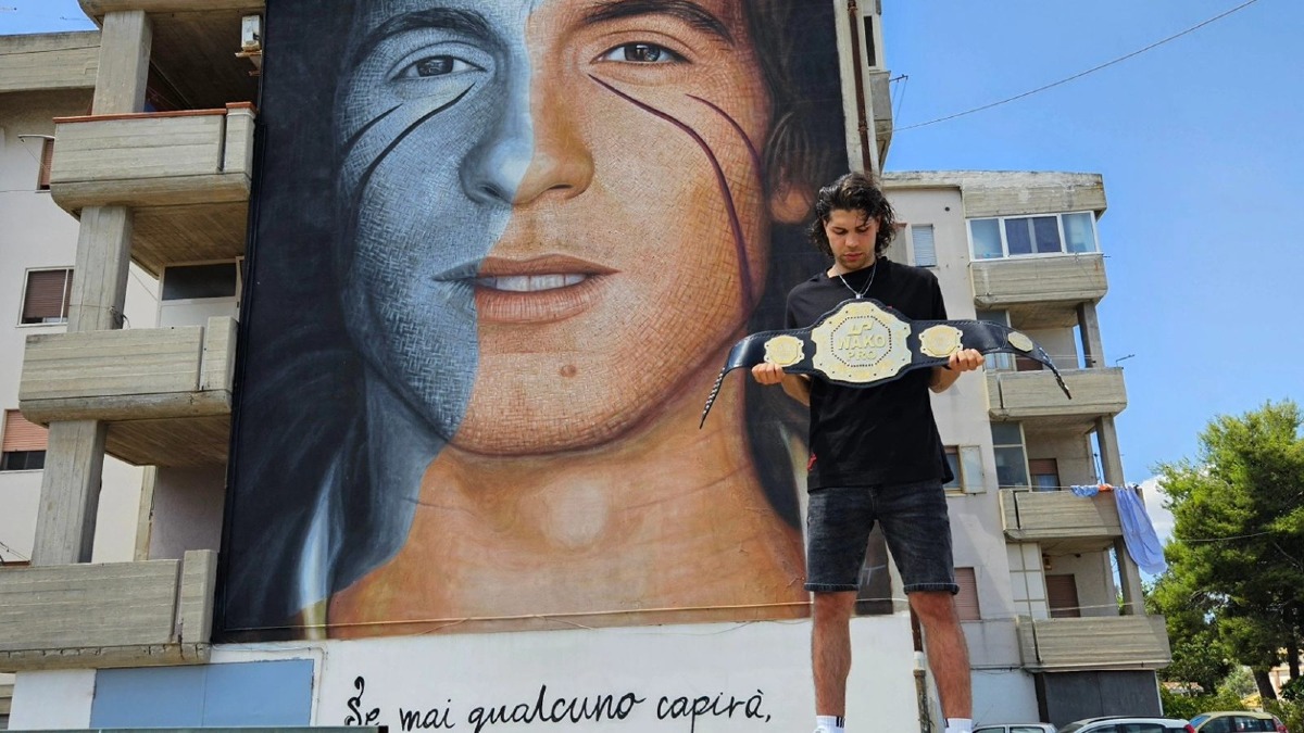 Fabrizio Ruggiero porta la cintura mondiale sotto il murale di Rino Gaetano - 