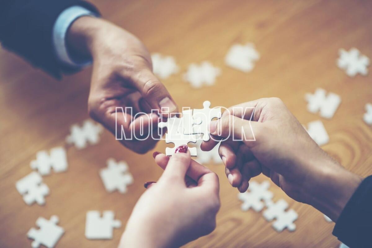 Apre a Crotone l’Emporio Solidale “Dacci Oggi…” della Caritas - hands trying to connect couple puzzle piece with background, one part of whole. symbol of association and connection. business strategy.